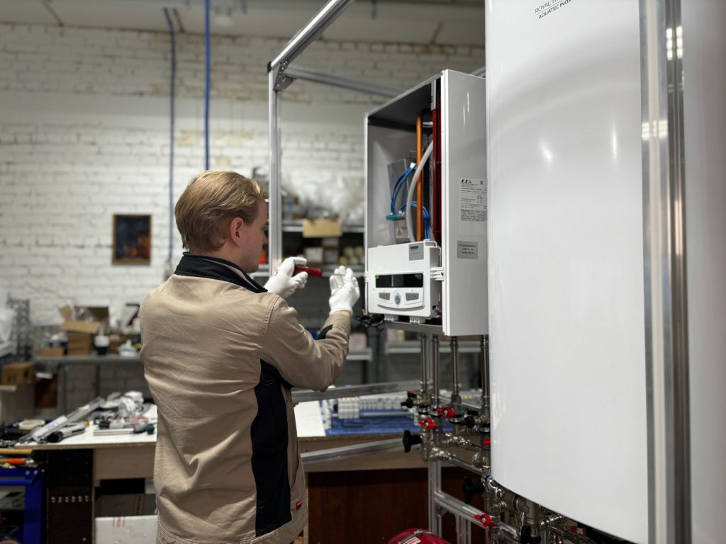 Ein Techniker inspiziert und repariert eine Heizungsanlage in einer industriellen Werkstatt.